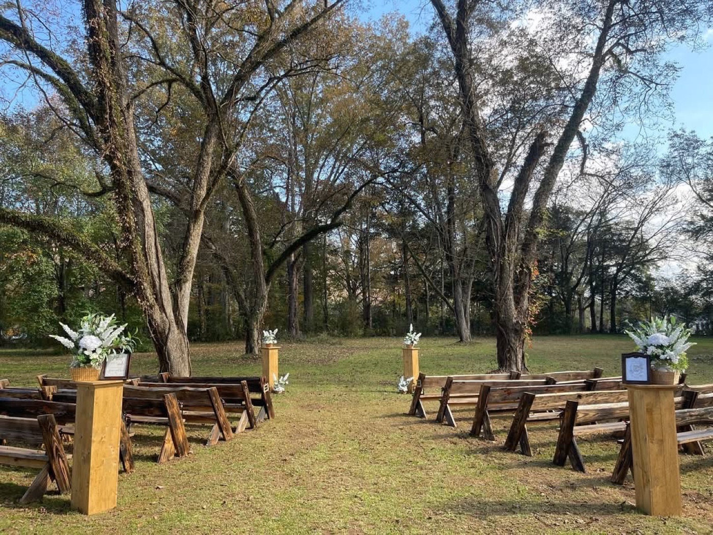 Outdoor wedding ceremony at Raulston Woods — wooden pews set along a natural aisle